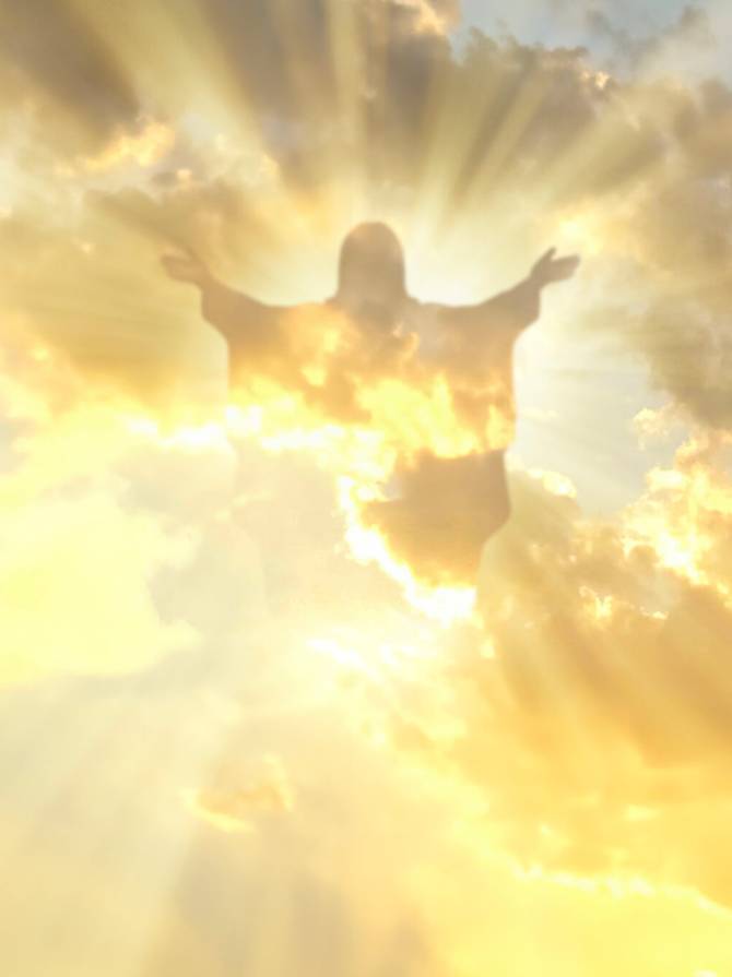 A silhouette of Jesus Christ in a sunny sky with clouds